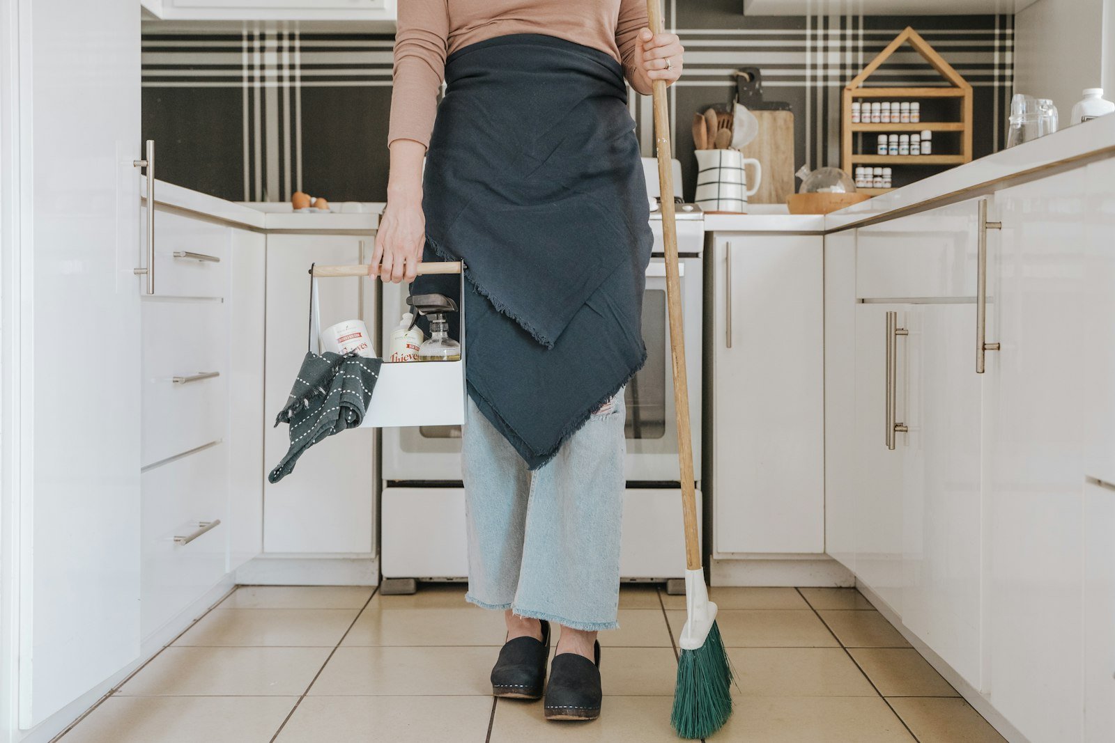 Woman holding broom in home kitchen