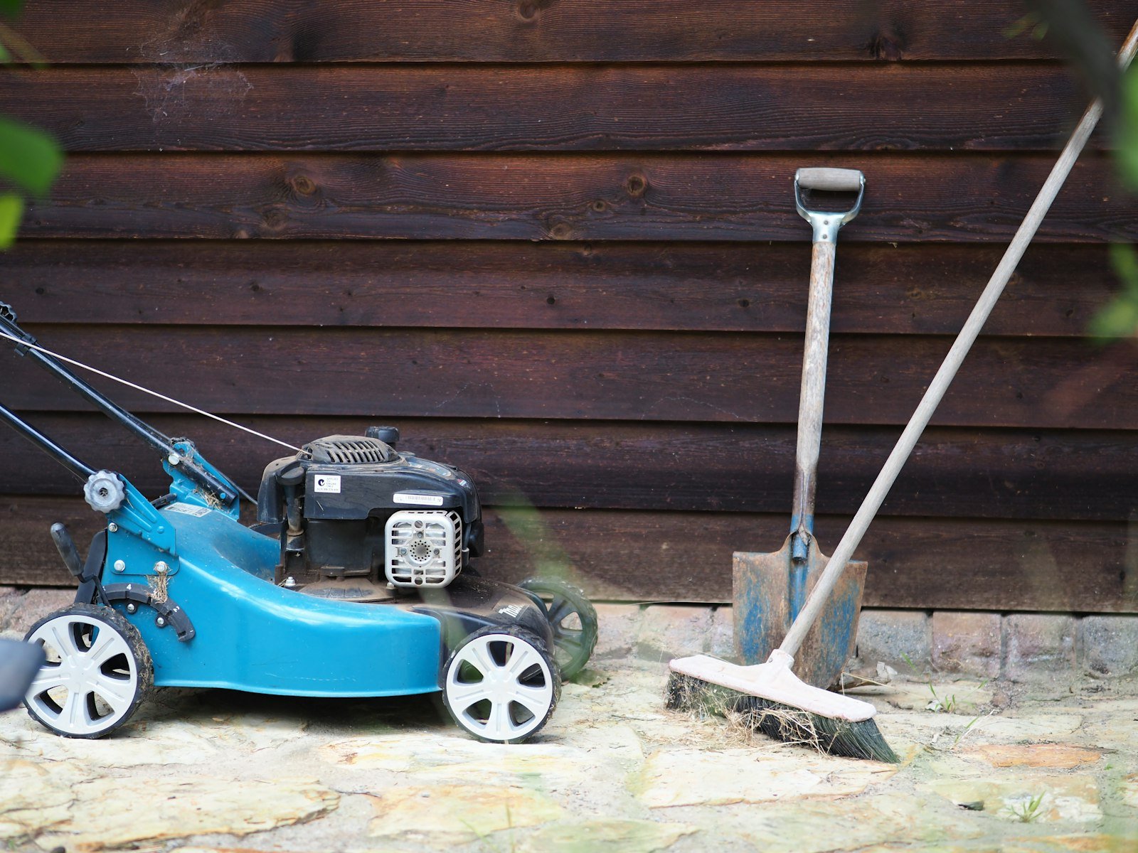 Lawn mower beside wooden wall