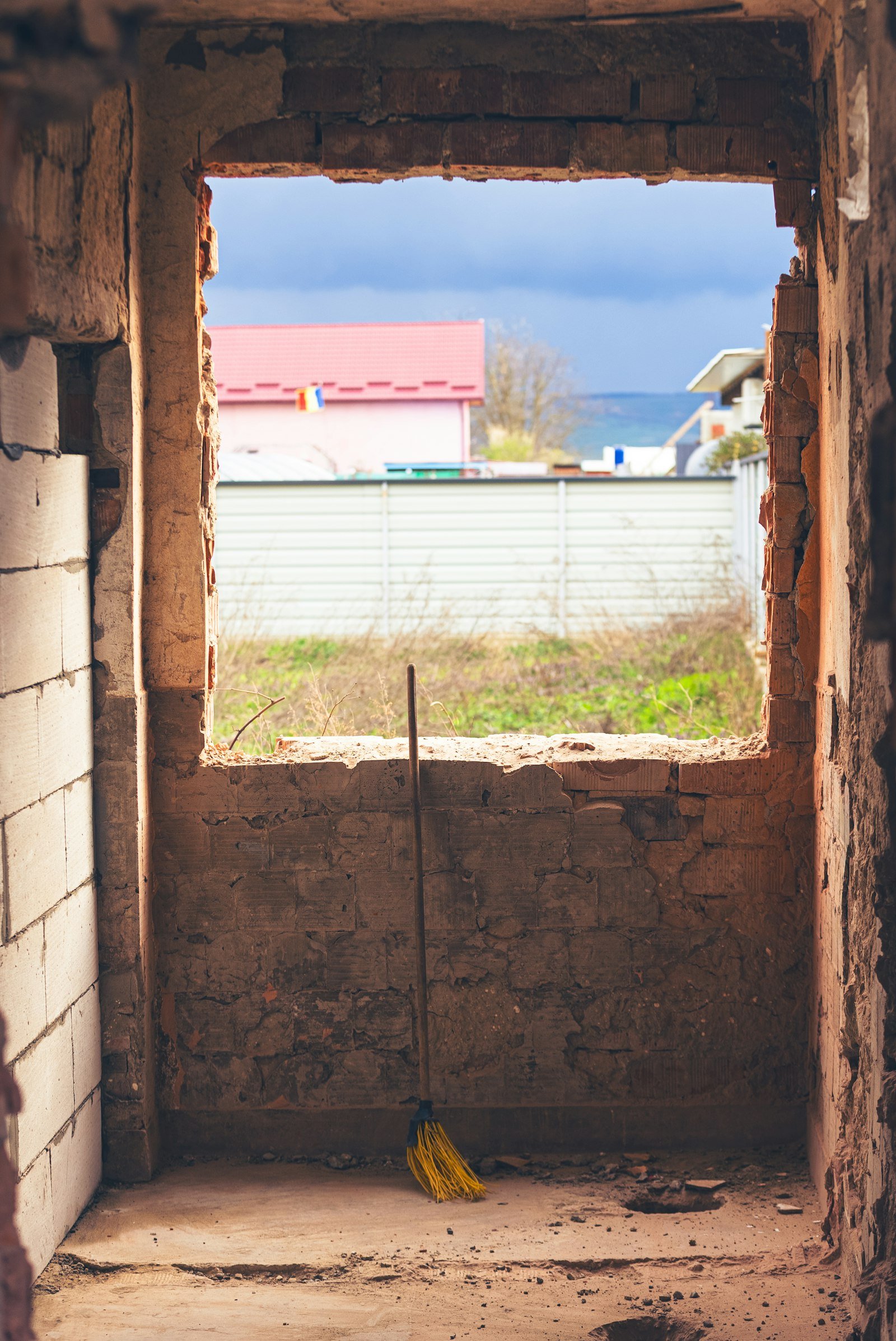 Broom against unfinished brick wall