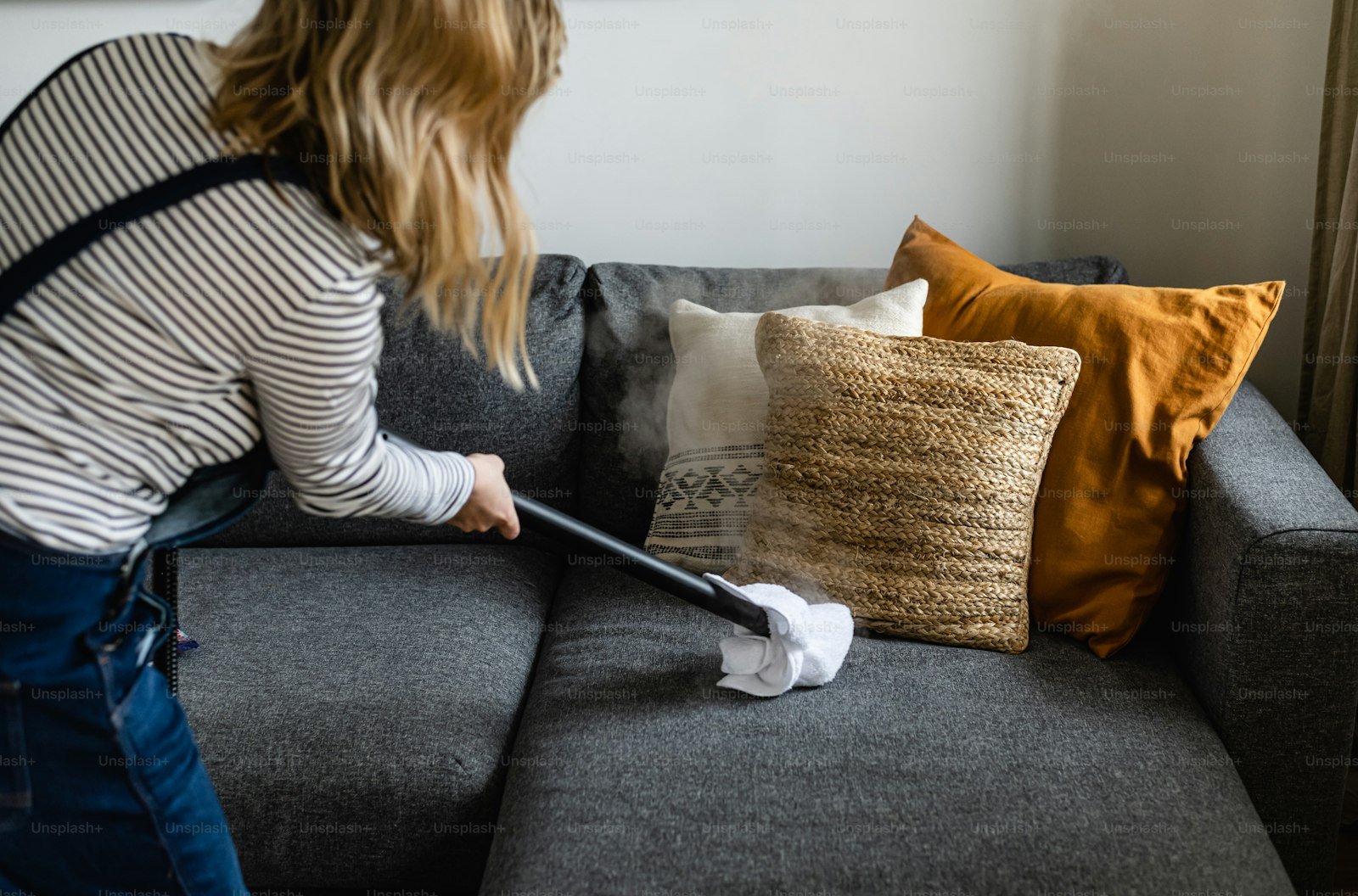 Cleaner vacuuming living-room sofa